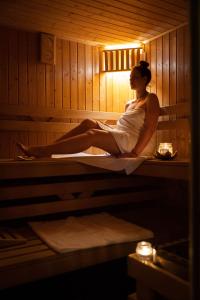 a woman is sitting in a sauna at Hotel Anek in Mrągowo