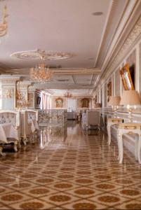Habitación grande con mesas, sillas y lámpara de araña. en Hotel Grand Aristocrate en Dubovtsy
