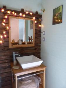 La salle de bains est pourvue d'un lavabo, d'un miroir et de lumières. dans l'établissement Au val des meuris, à Taintrux