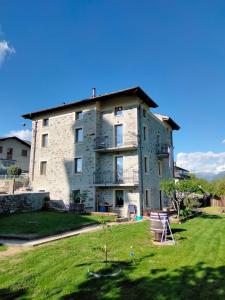 a large stone building with a lawn in front of it at Il posto al sole in Teglio