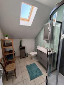 een badkamer met een wastafel, een toilet en een dakraam bij Chambres d'Hôtes Montjouan in Larochemillay
