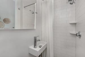 a white bathroom with a sink and a shower at Nantucket Periwinkle in Nantucket