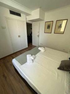 a white room with two beds and two towels at Apartamento IV AlcaláRetiro Ideal Parejas in Madrid