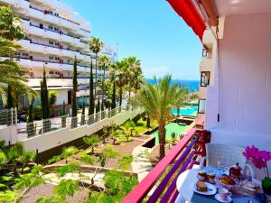 un balcón de un hotel con una mesa con comida en Miss Flora Olympia, en Playa de las Américas