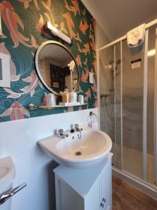 a bathroom with a sink and a mirror and a shower at Kirkcroft Guest House in Gretna