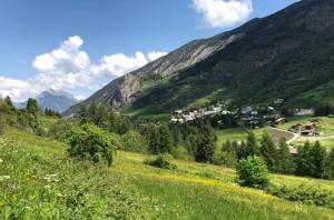 a green hillside with a small town in the mountains at Maison basse in Vars