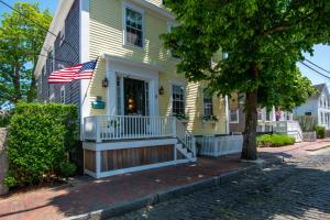 a yellow house with an american flag on the front porch at Nantucket Periwinkle in Nantucket