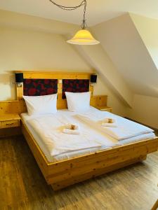 a bedroom with a large wooden bed with white sheets at Gasthaus Elsäßer Hof in Kappel-Grafenhausen