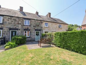 uma velha casa de pedra com um banco em frente em Carreg Cottage em Wrexham