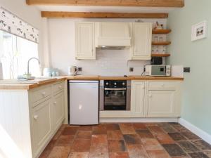 cocina con armarios blancos y suelo de baldosa en Carreg Cottage, en Wrexham