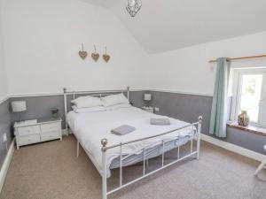 a bedroom with a white bed and a window at Carreg Cottage in Wrexham
