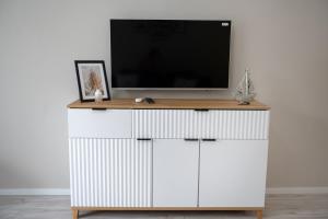 a tv on top of a white cabinet with a television on top at Blue Sea Apartment & SPA 8/2 in Dziwnów