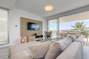 ein Wohnzimmer mit einem großen Sofa und einem TV in der Unterkunft Hillside house- Modern, upscale home w/SEA VIEWS in Estepona