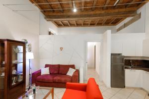 un soggiorno con divano rosso e una cucina di Appartamento Andrea Amati nel Cuore di Cremona a Cremona