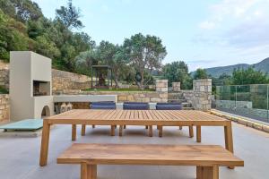 Agia TriadaにあるMoly - Luxury Villa with Heated Private Poolの木製テーブルとベンチ付きのパティオ(グリル付)