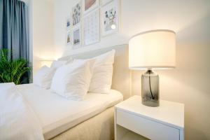 een slaapkamer met een bed met witte kussens en een lamp bij Urban Apartments in Brno