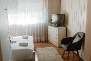 um pequeno quarto com uma cama, uma televisão e uma cadeira em Apartament Jutrzenka em Spytkowice