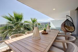 einen Holztisch auf dem Balkon eines Hauses in der Unterkunft Hillside house- Modern, upscale home w/SEA VIEWS in Estepona