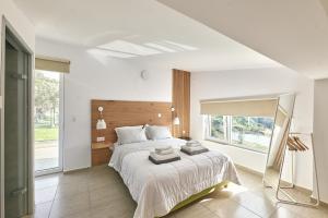 Agia TriadaにあるMoly - Luxury Villa with Heated Private Poolの白いベッドルーム(大型ベッド1台、窓付)