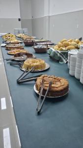 a long table with pies and tongs on it at Hotel Beirut in Aparecida