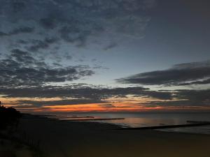 a sunset on a beach with the ocean at Blue Sea Apartment & SPA 8/2 in Dziwnów