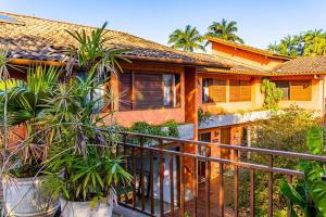 uma casa com uma varanda com plantas em frente em Pousada Jamboo em Ubatuba