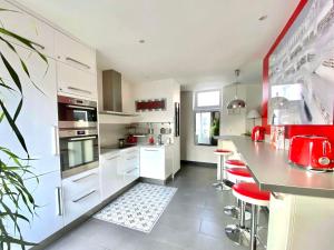 a kitchen with white cabinets and a counter with red accents at LESPARISNORMANDS - le duplex de la reine in Boulogne-Billancourt