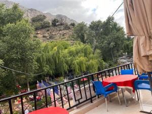 a balcony with a red table and blue chairs at Hôtel Restaurant ASGAOUR in Amlouggui