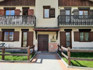 a house with wooden doors and a fence at Le Chat Riant in Fenis