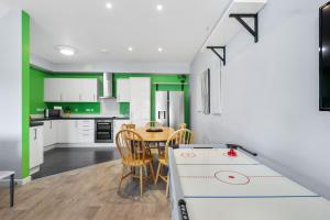a kitchen with white cabinets and a table and chairs at Modern Eco House With Parking in Brighton & Hove