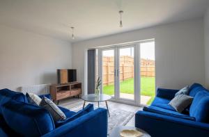 a living room with two blue couches and a window at Lovely brand new 3 bedroom city centre house with garden in Derby
