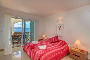 a bedroom with a red bed and a balcony at Villa Katarina in Stanići +41 photos