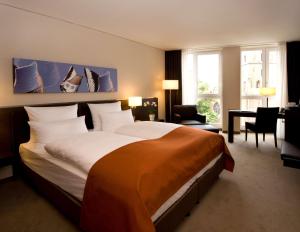 a hotel room with a large bed and a desk at Atlantic Grand Hotel Bremen in Bremen
