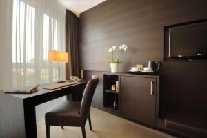 a room with a desk with a chair and a television at Atlantic Grand Hotel Bremen in Bremen