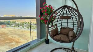 una silla colgante con almohadas en una habitación con ventana en Desert Flower Delight, en Al Qurayyah