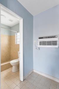 a bathroom with a toilet and a air conditioner at Deluxe Inn in Dania Beach