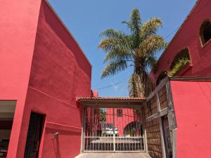 天波佐特蘭的住宿－Suite Nube, Experiencia Única, Nómadas Digitales, Home Office o Vacacional，一座红色的建筑,有大门和棕榈树