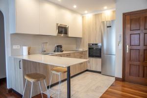 a kitchen with a island with stools and a refrigerator at Egona- Vivienda en el centro de Zarautz a 1 min de la playa in Zarautz