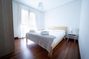 a white bedroom with a bed with two towels on it at Egona- Vivienda en el centro de Zarautz a 1 min de la playa in Zarautz