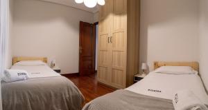 a bedroom with two beds and a wooden door at Egona- Vivienda en el centro de Zarautz a 1 min de la playa in Zarautz