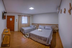 um quarto com 2 camas e piso em madeira em Pousada Vento Sul em Chapada dos Guimarães