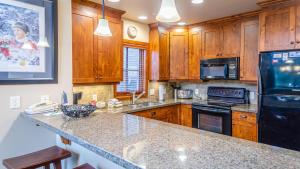 a kitchen with wooden cabinets and a black refrigerator at Woodhaven #32 By Bear Country in Sun Peaks