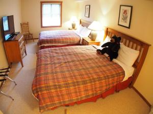 a bedroom with two beds and a teddy bear sitting on the bed at Fireside Lodge #302 By Bear Country in Sun Peaks