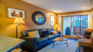 a living room with a blue couch and a table at Snow Creek Village #48 By Bear Country in Sun Peaks