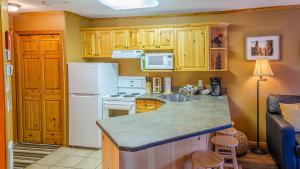 a kitchen with a white refrigerator and a counter top at Snow Creek Village #48 By Bear Country in Sun Peaks