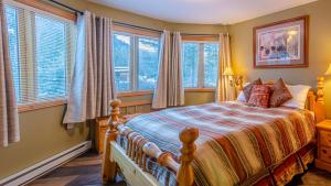a bedroom with a bed with windows and a bedspread at Snow Creek Village #48 By Bear Country in Sun Peaks