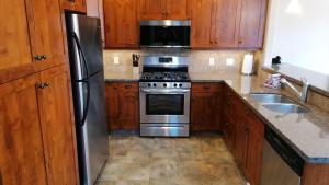 una cocina con electrodomésticos de acero inoxidable y armarios de madera en Woodhaven #19 by Bear Country, en Sun Peaks