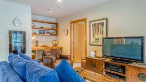 a living room with a blue couch and a tv at Kookaburra Lodge #303 By Bear Country in Sun Peaks