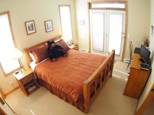 a bedroom with a large bed with a teddy bear on it at Crystal Forest #66 By Bear Country in Sun Peaks