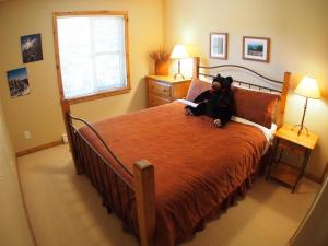 a teddy bear sitting on a bed in a bedroom at Crystal Forest #66 By Bear Country in Sun Peaks